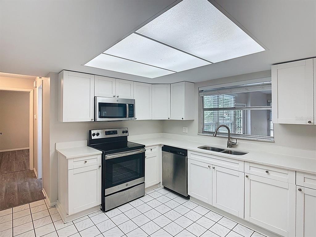 11320 Currie Lane Largo, FL 33774 - Photo 5 of 40 a kitchen with white cabinets stainless steel appliances and a sink