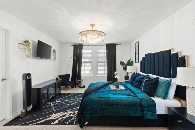 a bedroom with a bed a couch and a flat tv screen on the dresser