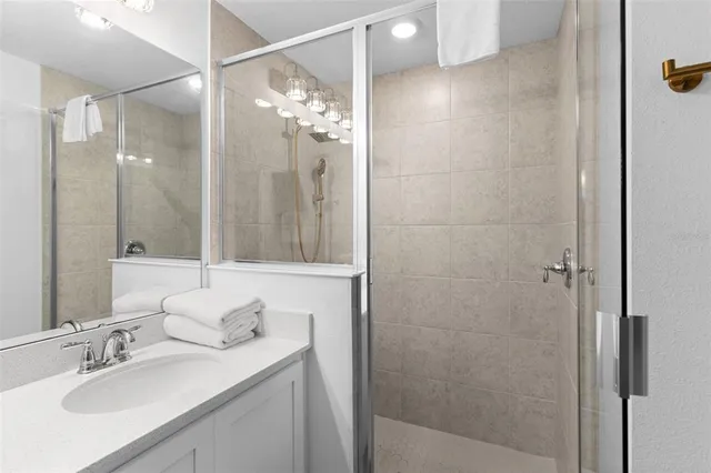 a bathroom with a sink vanity granite shower and a mirror
