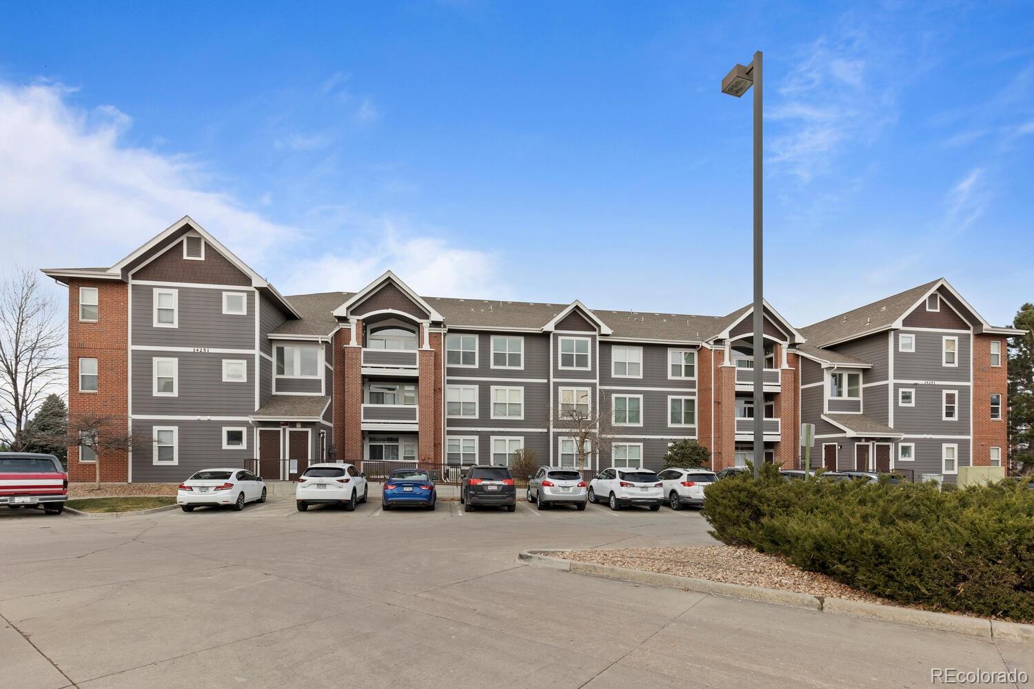 14251 East 1st Drive, Unit 305 Aurora, CO 80011 - Photo 21 of 22 a front view of a building with lot of cars parked on road