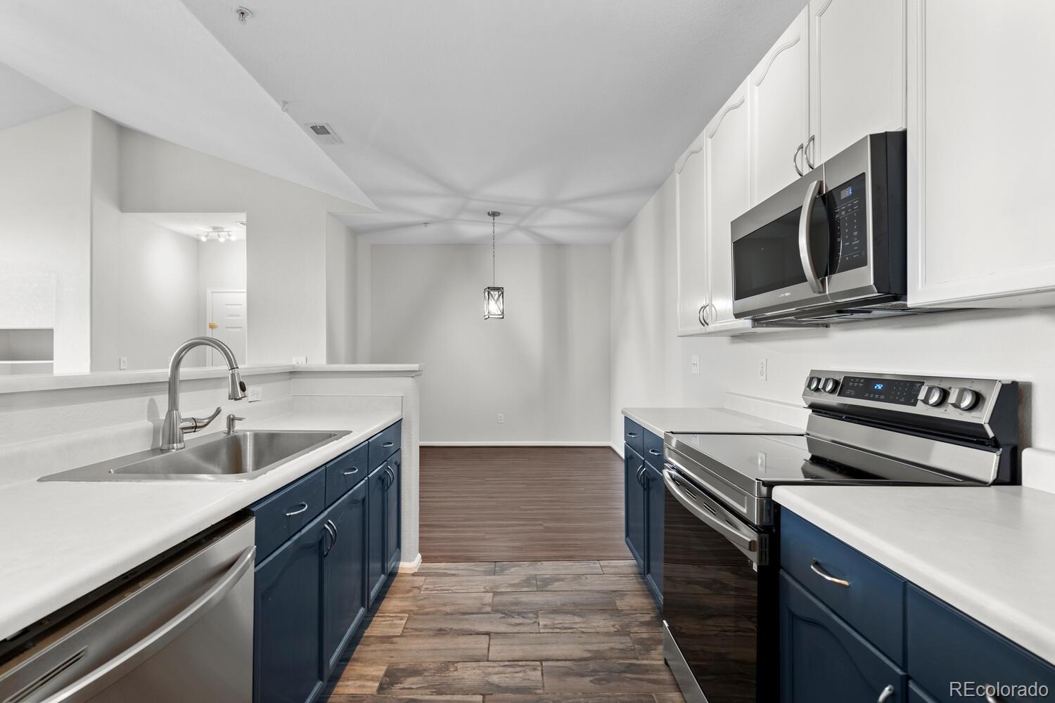 14251 East 1st Drive, Unit 305 Aurora, CO 80011 - Photo 7 of 22 a kitchen with stainless steel appliances granite countertop a sink stove and microwave