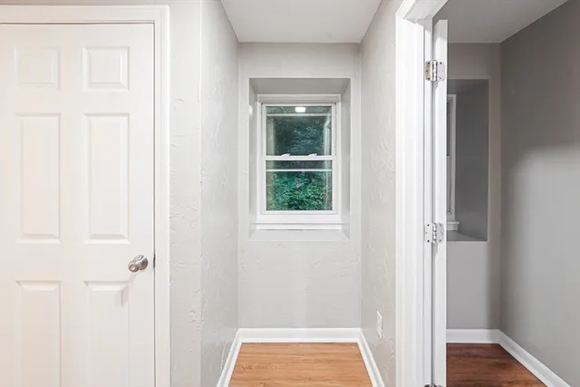 a view of an empty room with wooden floor and a window