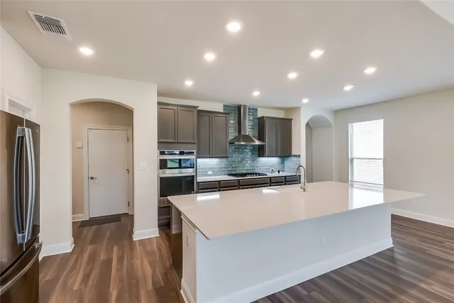 a large kitchen with stainless steel appliances a large counter top a stove and a refrigerator