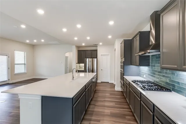 a large kitchen with stainless steel appliances kitchen island granite countertop a large counter top and wooden floors