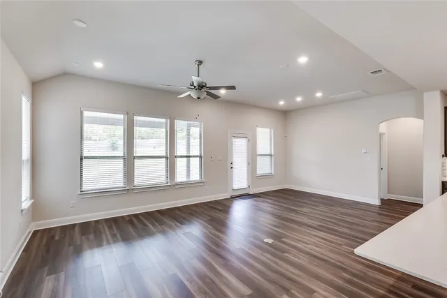 a view of an empty room with a window and wooden floor