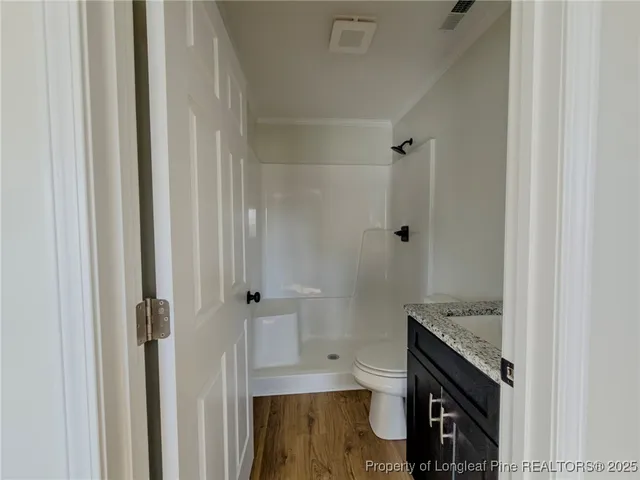 a bathroom with a granite countertop sink a toilet and shower