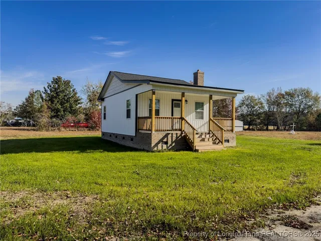 a front view of house with yard and trees in the background