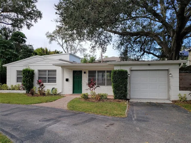 a front view of house with yard and trees in the background
