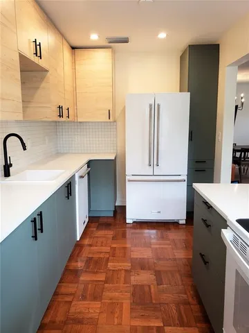 a kitchen with kitchen island a counter top space a sink a refrigerator and cabinets