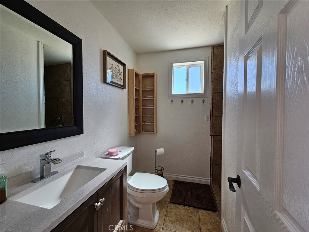 3939 Pinto Mountain Road Twentynine Palms, CA 92277 - Photo 16 of 47 a bathroom with a granite countertop toilet sink and mirror