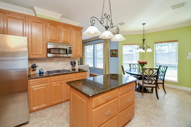 a kitchen with cabinets a counter space dining table and stainless steel appliances
