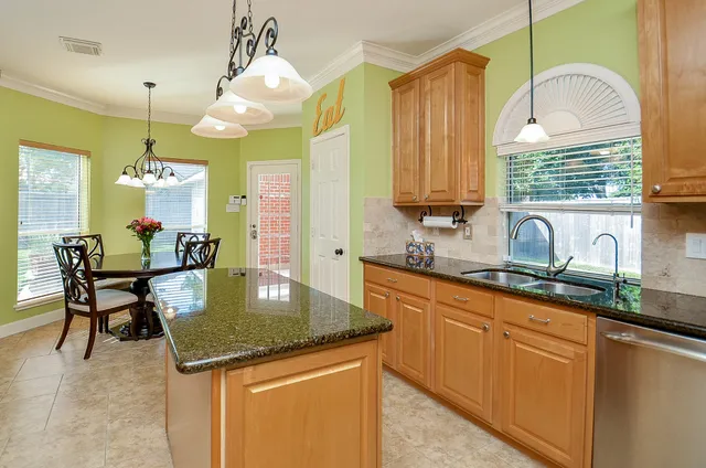 a kitchen with kitchen island granite countertop a sink a counter top space and living room view