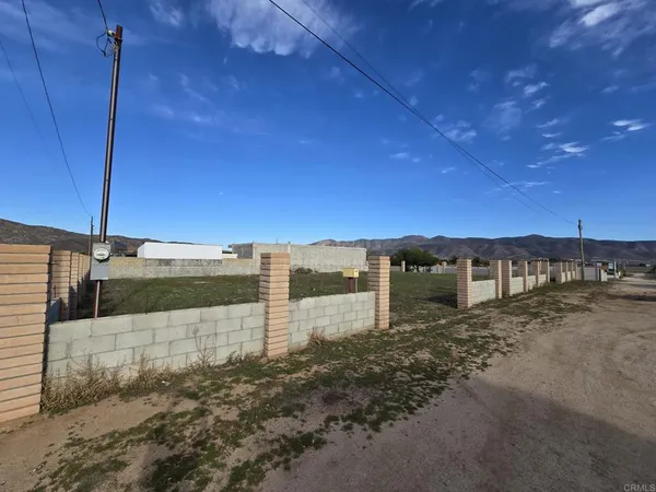 a view of a dry yard with wooden fence