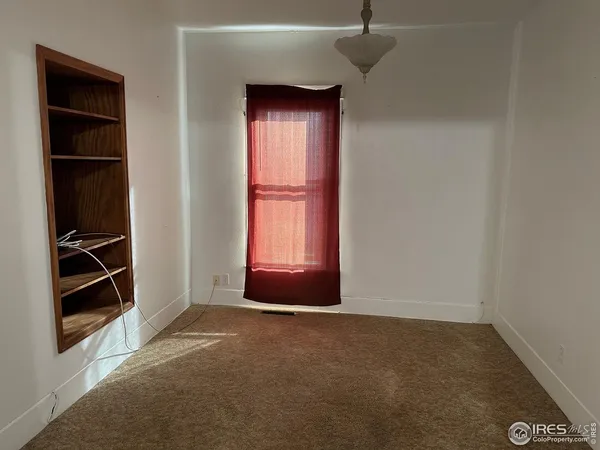 a view of an empty room with closet and a window