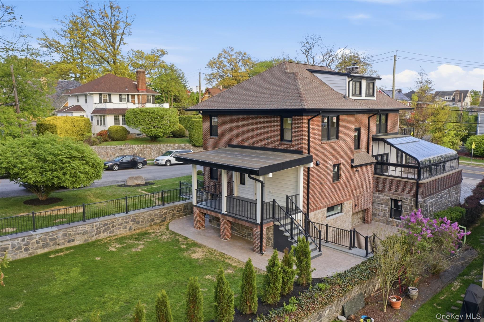 40 Calhoun Avenue New Rochelle, NY 10801 - Photo 44 of 49 Brick exterior residence featuring a sunroom addition, a rear covered porch, and a patio with an exterior staircase