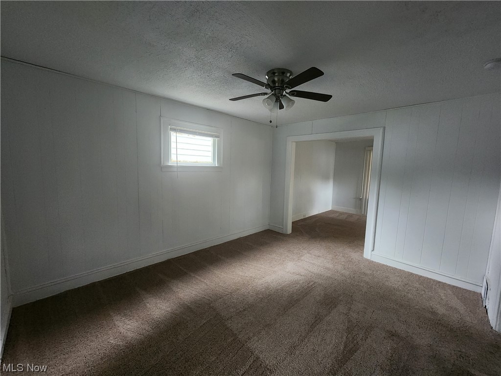 13417 Rugby Road Cleveland, OH 44110 - Photo 9 of 26 Unfurnished room with ceiling fan, a textured ceiling, and dark carpet
