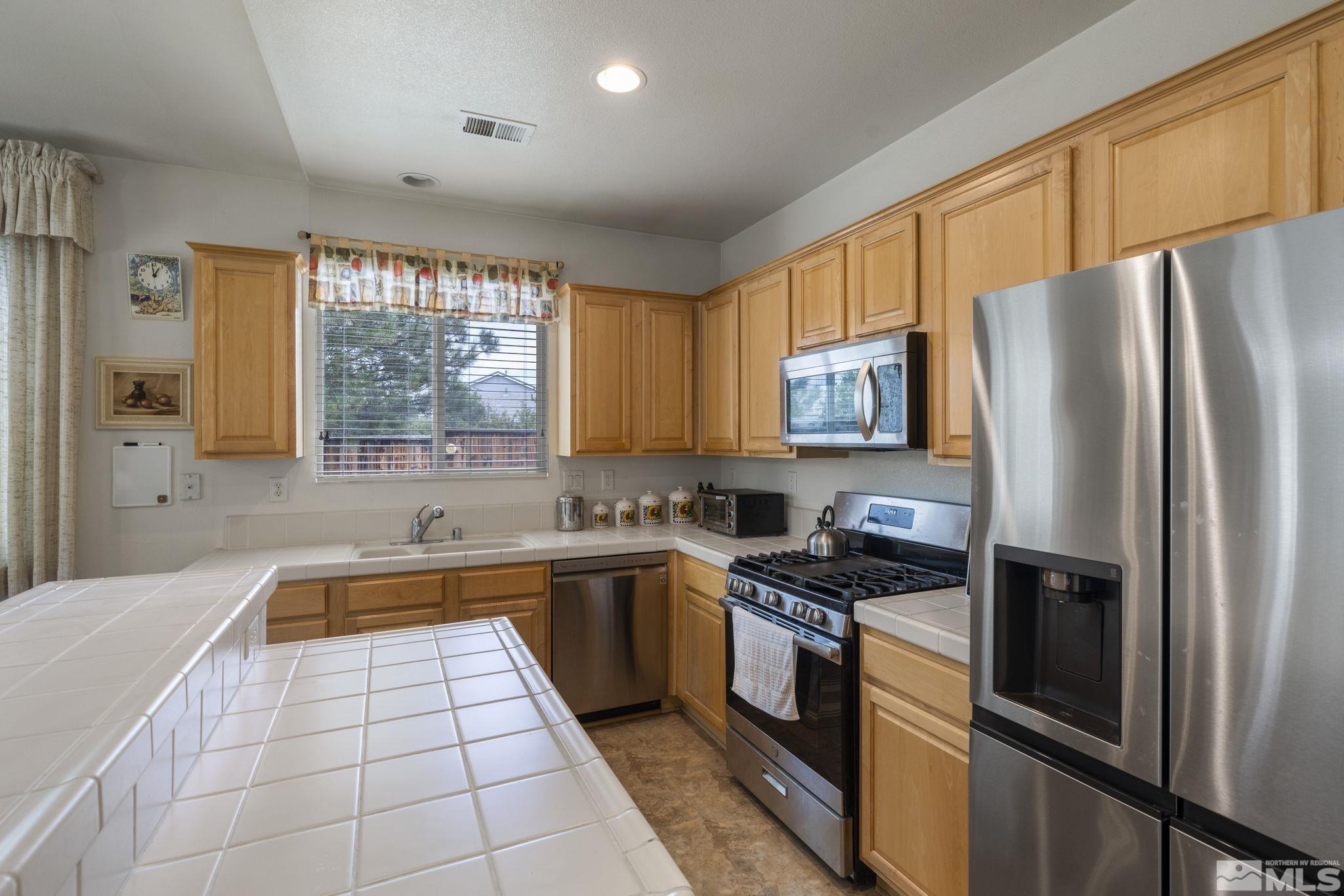 1620 Rocky Cove Lane Reno, NV 89521 - Photo 15 of 35 a kitchen with stainless steel appliances granite countertop a refrigerator a sink dishwasher a stove with open cabinets and wooden floor