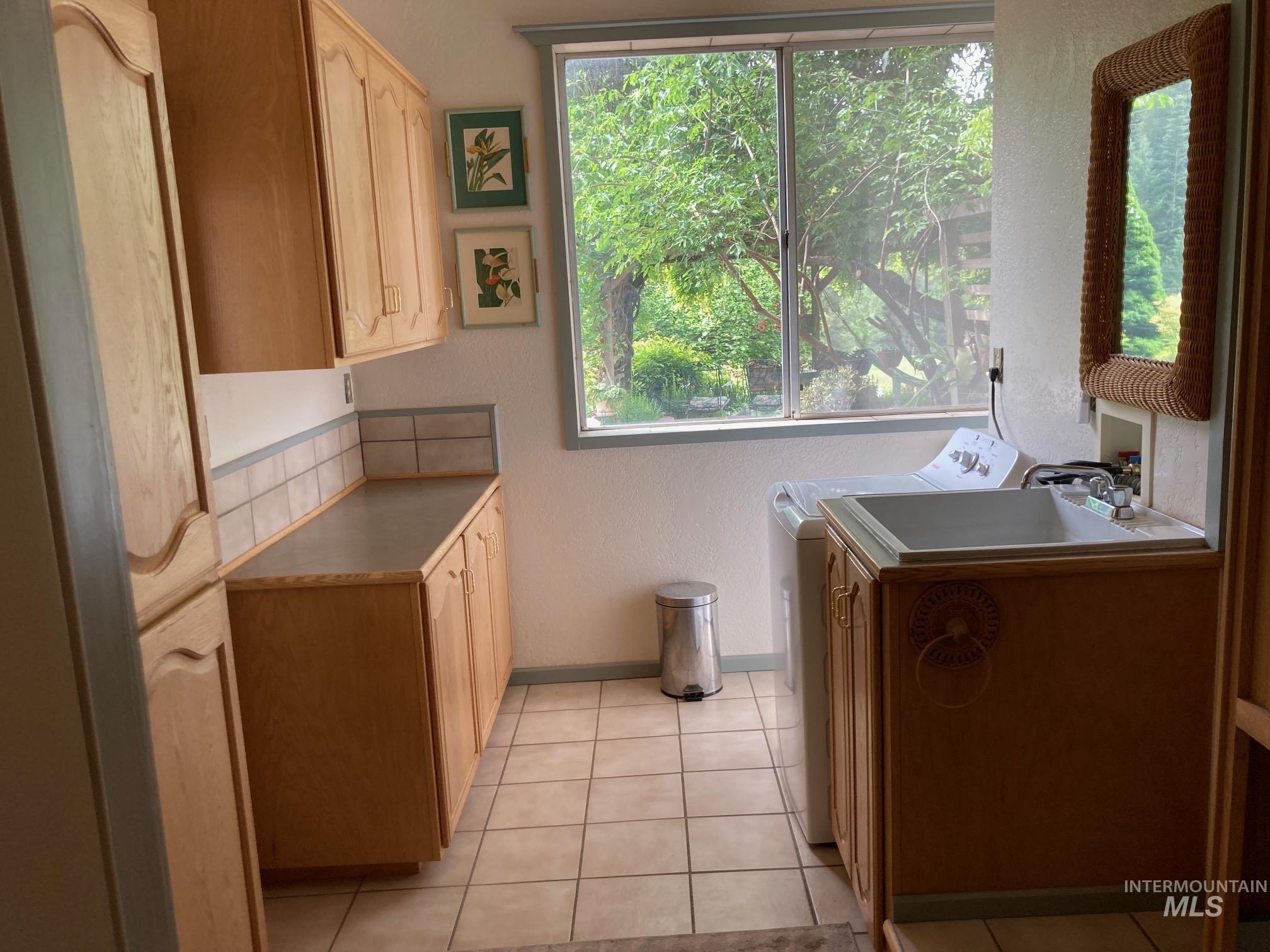266 Falcon Ridge Road Kooskia, ID 83539 - Photo 23 of 50 Utility room with wood-finish cabinetry, tile flooring, and a large window