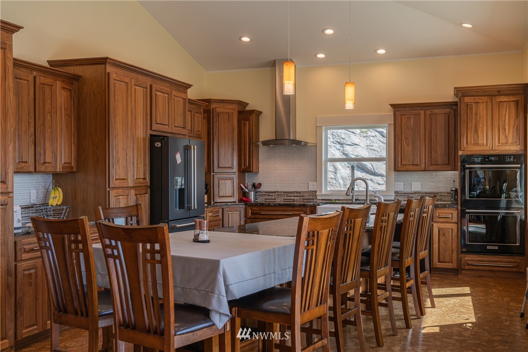 70 B Tunk Creek Road Riverside, WA 98849 - Photo 12 of 40 a kitchen with stainless steel appliances granite countertop a table chairs and a refrigerator