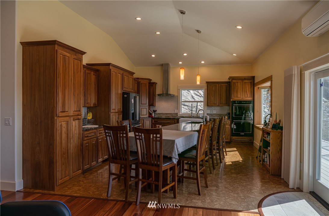 70 B Tunk Creek Road Riverside, WA 98849 - Photo 13 of 40 a kitchen with stainless steel appliances a refrigerator a stove a dining table and chairs with wooden floor