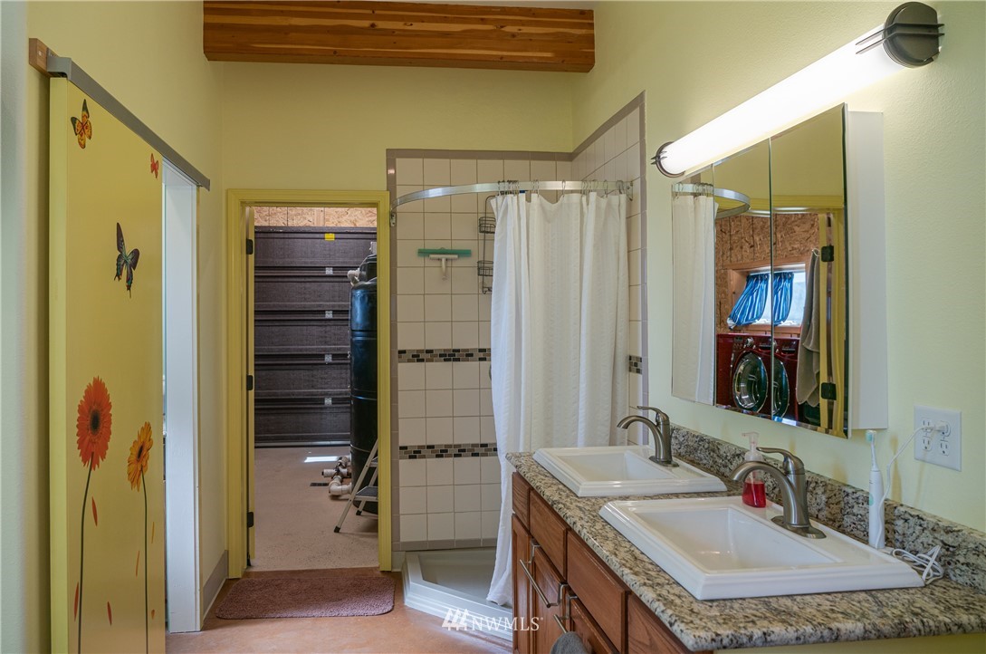 70 B Tunk Creek Road Riverside, WA 98849 - Photo 34 of 40 a bathroom with a granite countertop shower a sink and a mirror