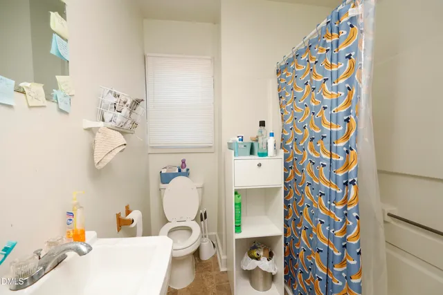 a bathroom with a sink toilet and shower curtain