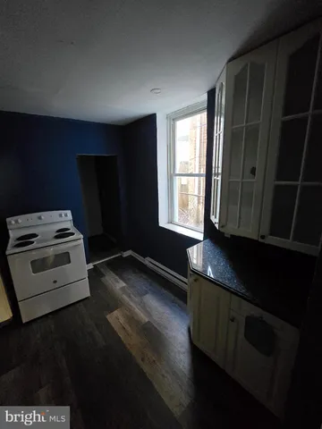 a kitchen with granite countertop wooden cabinets stove and sink