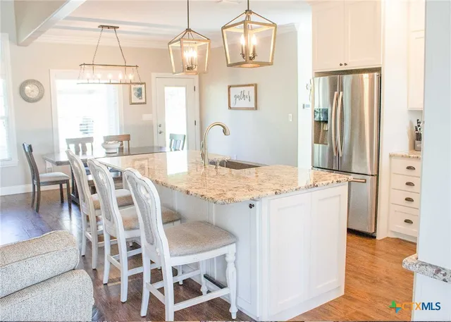 a kitchen with kitchen island granite countertop a stove a sink a counter space and wooden floor