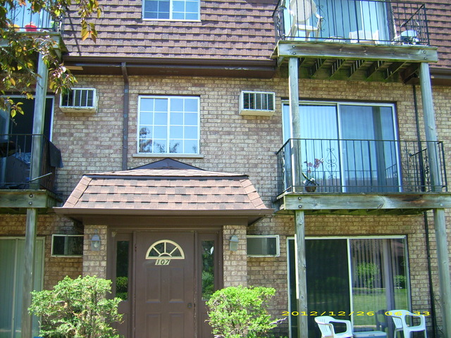 a view of a brick house with large windows and a flower plants