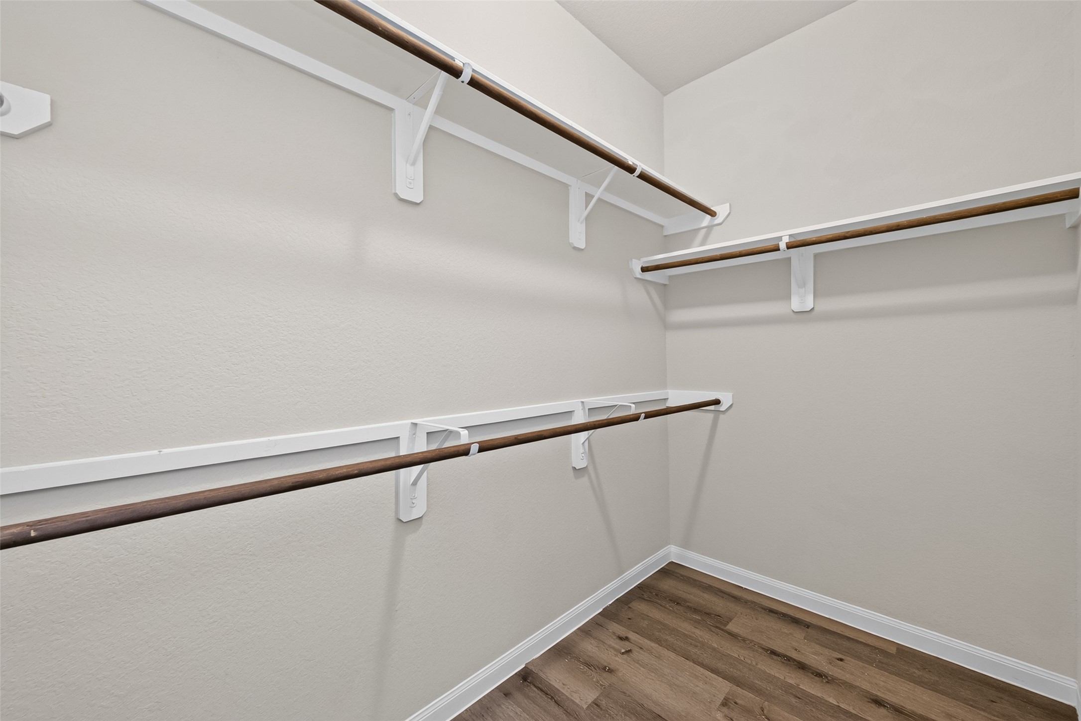 2526 Sturgeon Way Conroe, TX 77384 - Photo 26 of 49 This is a spacious walk-in closet featuring multiple wooden hanging rods and a neutral color palette, complemented by wood-look flooring.