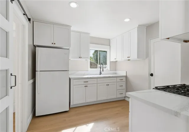 a kitchen with white cabinets and refrigerator
