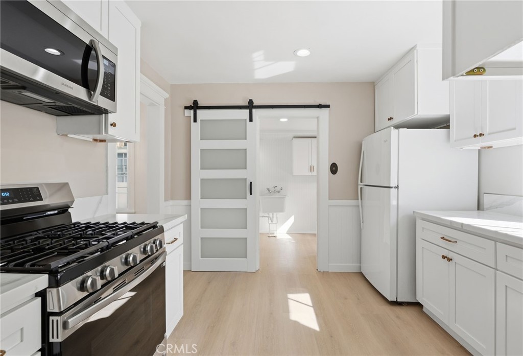 3756 Locust Street Riverside, CA 92501 - Photo 13 of 22 a kitchen with stainless steel appliances a refrigerator a sink and white cabinets