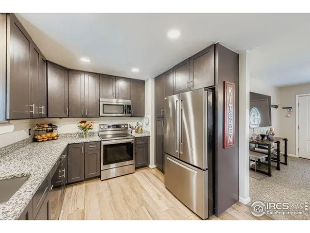 a kitchen with stainless steel appliances granite countertop a refrigerator a stove and a sink with wooden cabinets