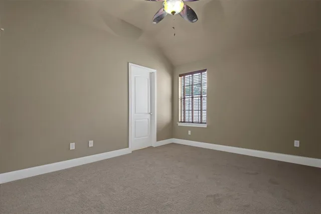 an empty room with a chandelier fan and windows