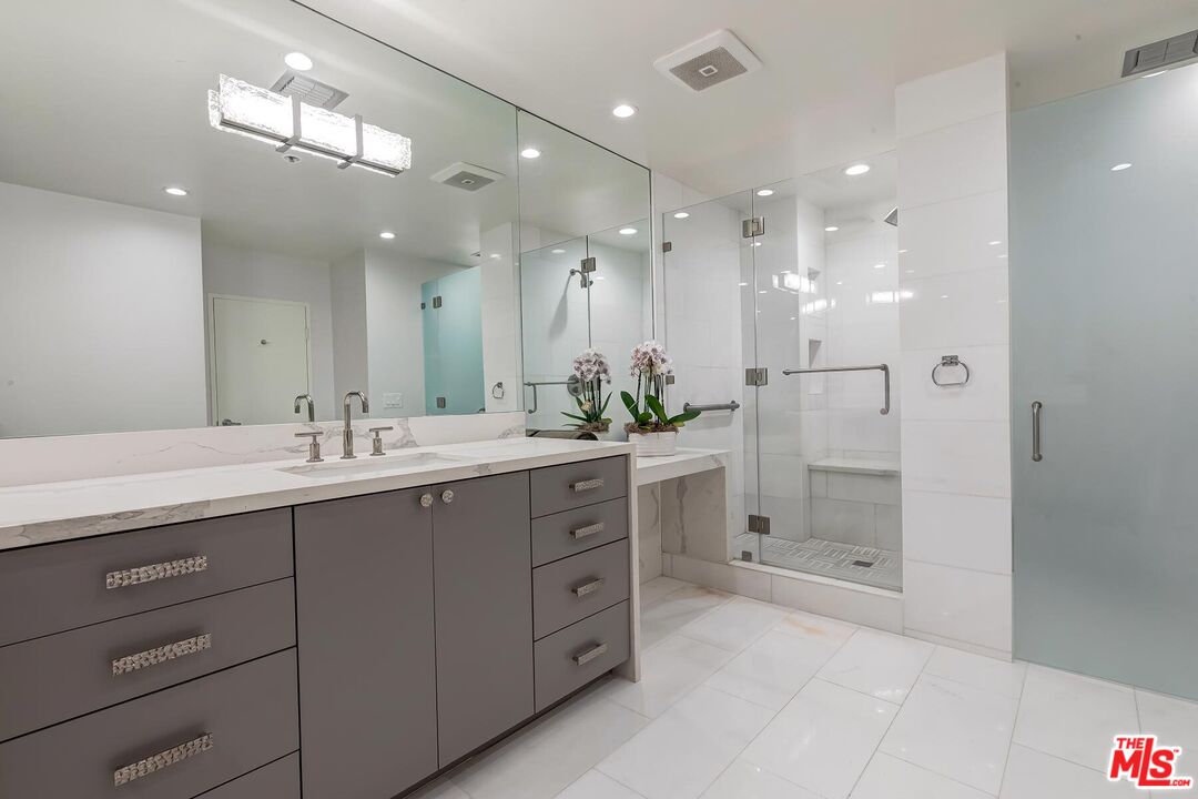 10430 Wilshire Boulevard, Unit 803 Los Angeles, CA 90024 - Photo 13 of 23 a bathroom with a granite countertop sink mirror and shower