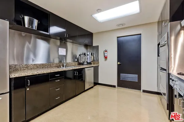 a kitchen with stainless steel appliances granite countertop a refrigerator a sink and a stove
