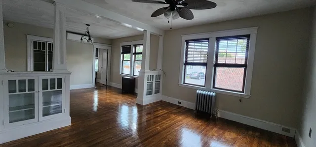a view of an empty room with wooden floor and a window