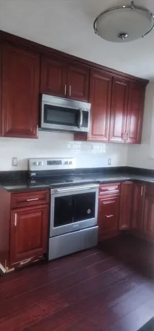 a kitchen with granite countertop wood cabinets stainless steel appliances and wooden floor