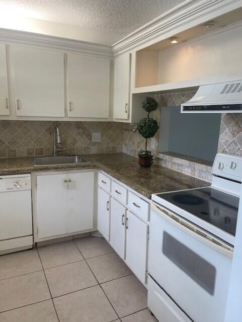 2901 Fiore Way, Unit 103 Delray Beach, FL 33445 - Photo 25 of 29 a kitchen with granite countertop white cabinets and white appliances