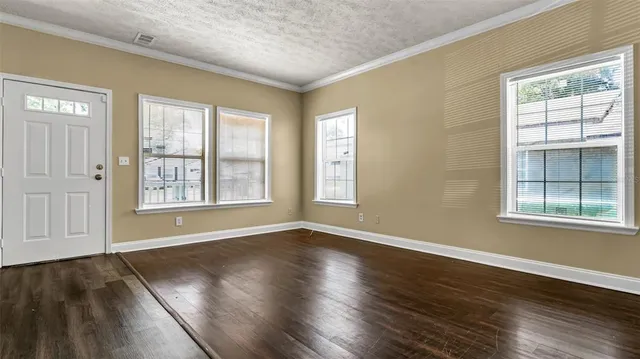 a view of an empty room with wooden floor and a window