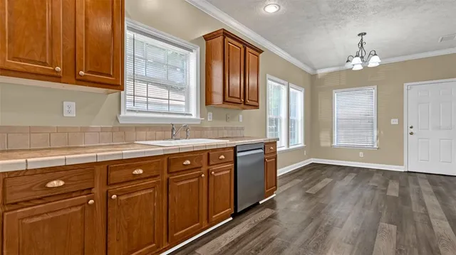 a kitchen with stainless steel appliances granite countertop wooden cabinets a sink and dishwasher with wooden floor