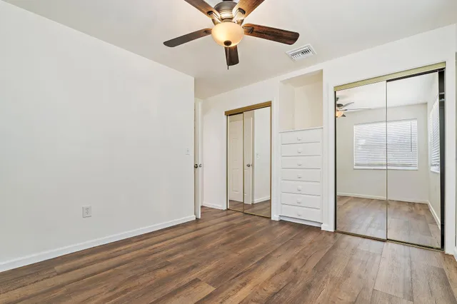 an empty room with closet and a ceiling fan