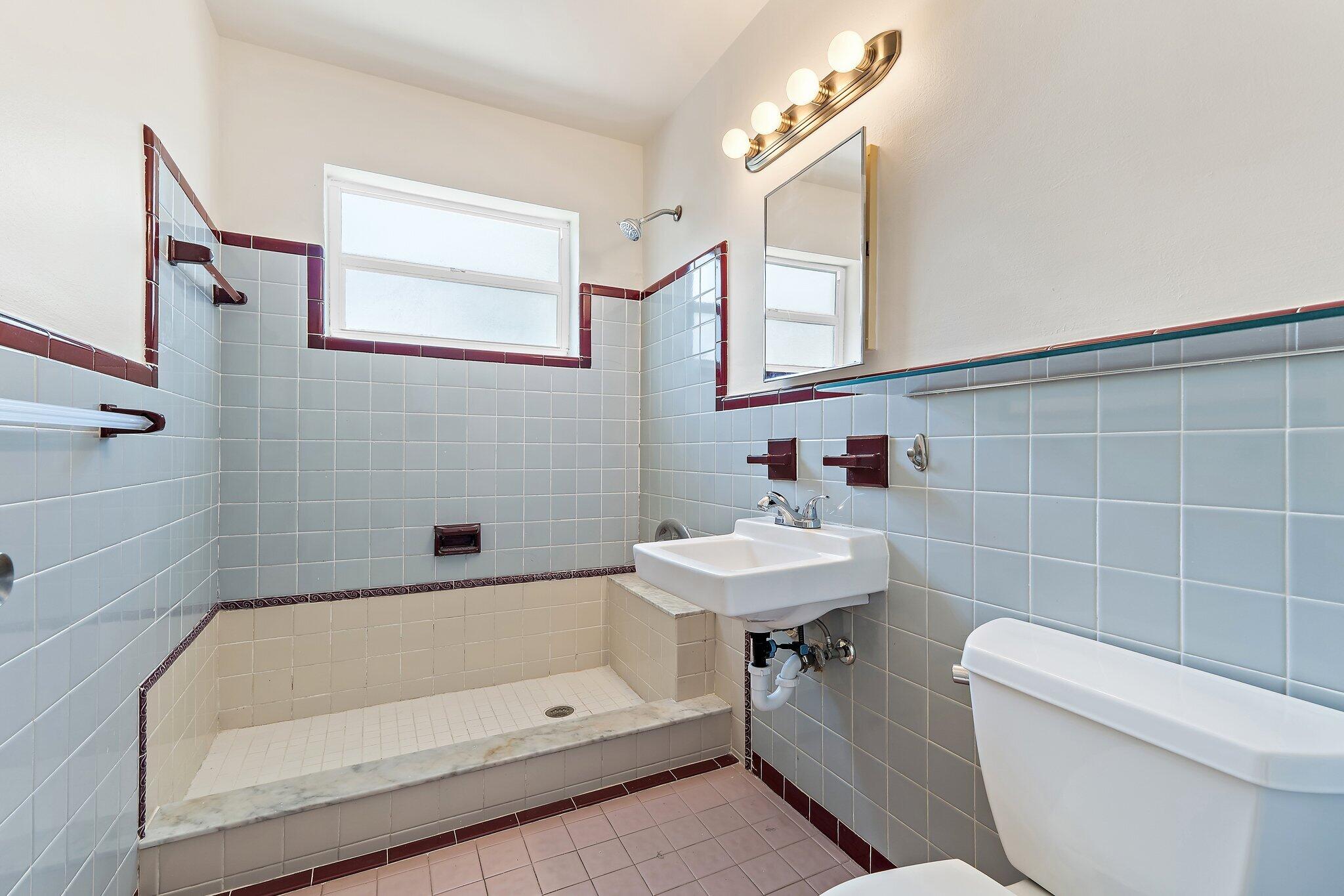 19147 Southeast Hillcrest Drive, Unit A Jupiter, FL 33469 - Photo 14 of 17 a bathroom with a sink a toilet and shower