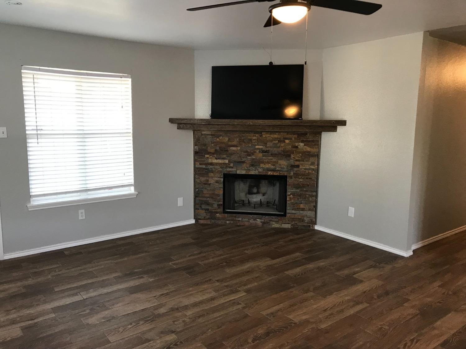 6201 5th Street Lubbock, TX 79416 - Photo 12 of 32 a living room with a fireplace and a flat screen tv