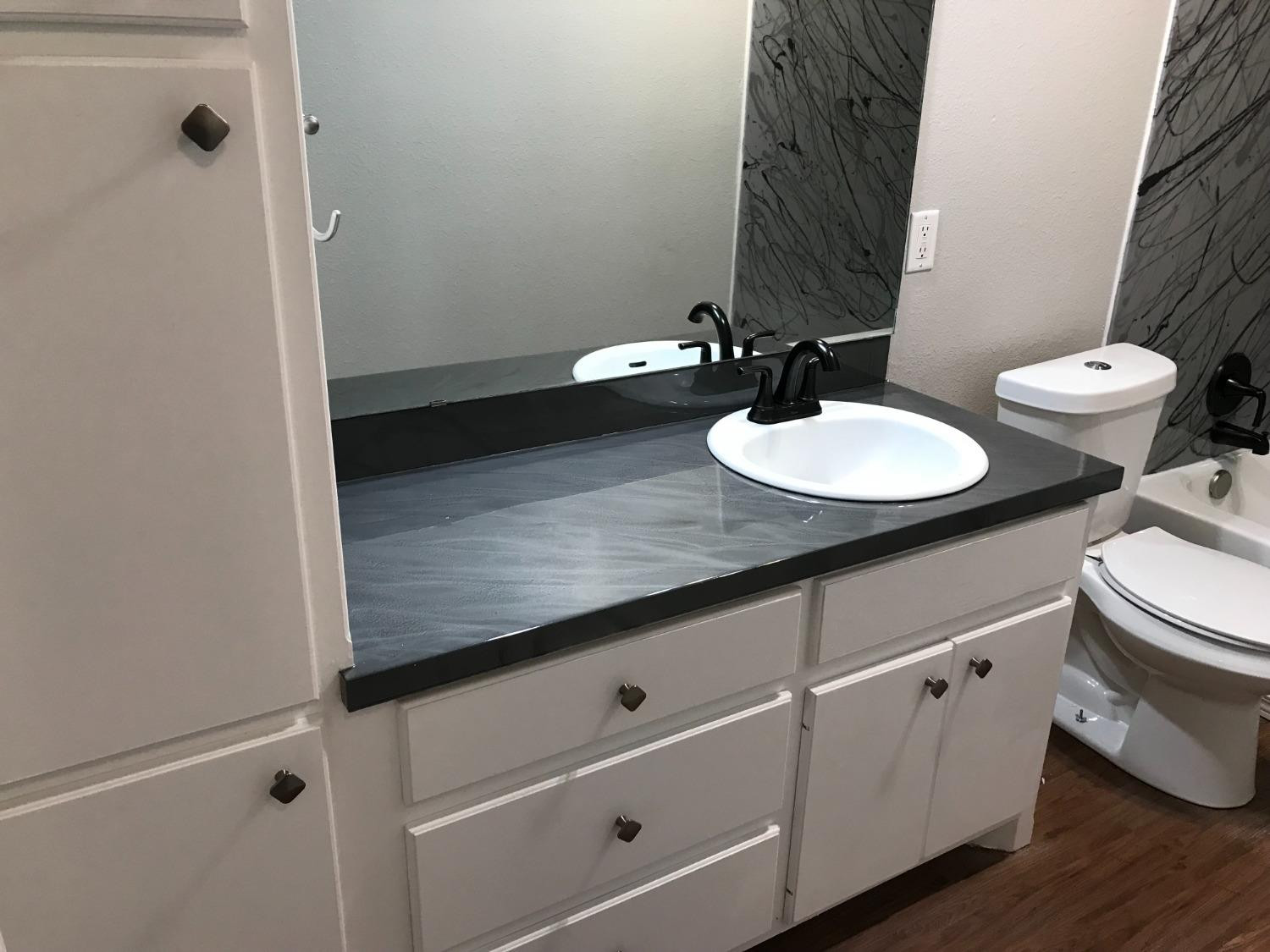 6201 5th Street Lubbock, TX 79416 - Photo 29 of 32 a bathroom with a granite countertop sink and a mirror