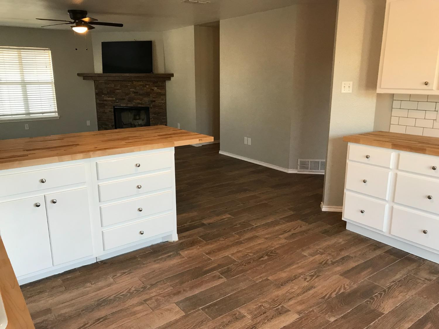 6201 5th Street Lubbock, TX 79416 - Photo 5 of 32 a kitchen with a wooden floor and a fireplace