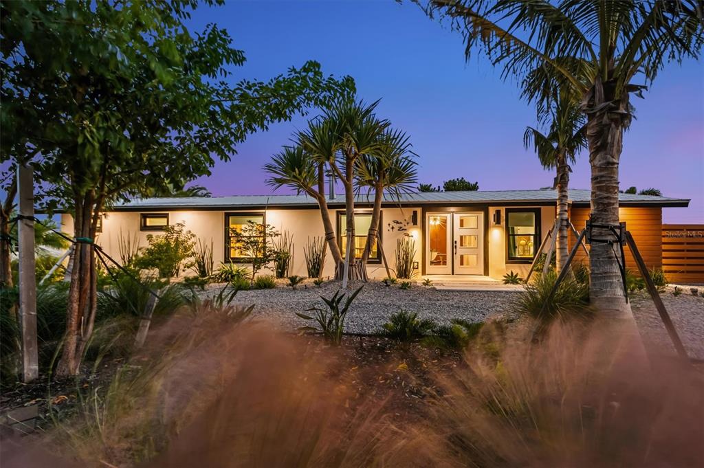 505 65th Street Holmes Beach, FL 34217 - Photo 51 of 64 a view of swimming pool with table and chairs under an umbrella with palm trees