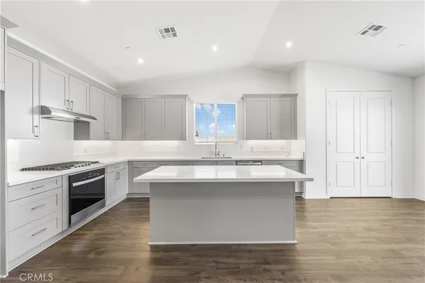 a kitchen with kitchen island sink stove and white cabinets