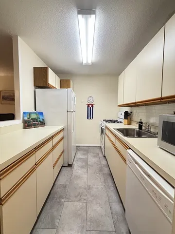 a large white kitchen with stainless steel appliances granite countertop a sink and cabinets