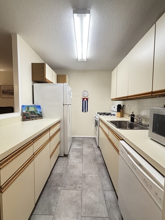 2 Hawthorne Place, Unit 7O Boston, MA 02114 - Photo 8 of 17 a large white kitchen with stainless steel appliances granite countertop a sink and cabinets